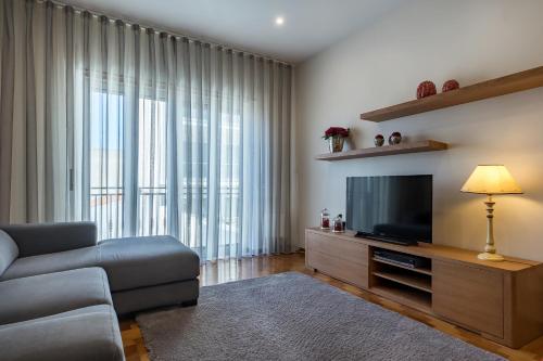 a living room with a couch and a flat screen tv at Sea & Relax Villa Nazaré in Nazaré