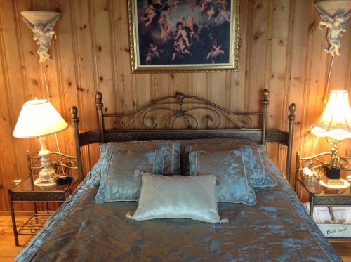 a bedroom with a bed with two lamps and a picture on the wall at Gite la Tourelle du Cap in La Malbaie