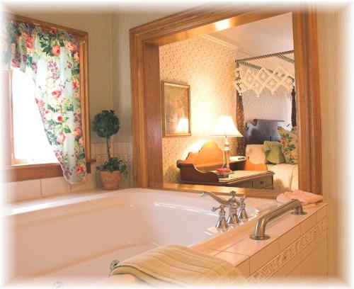 a bathroom with a bath tub and a large mirror at White Lace Inn in Sturgeon Bay