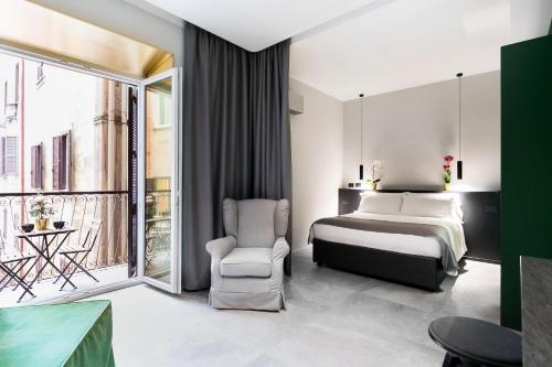 ein Schlafzimmer mit einem Bett und einem Stuhl und einem Fenster in der Unterkunft Etruscan Luxury Suites in Rom