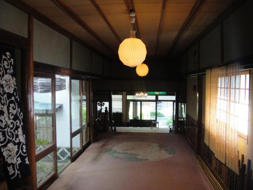 an empty hallway with a room with windows and a chandelier at Kurhaus Ishibashi Ryokan in Shimoda