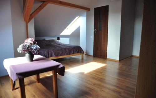 a bedroom with a bed and a table with a vase of flowers at Modrzewiowe Wzgorze in Promno