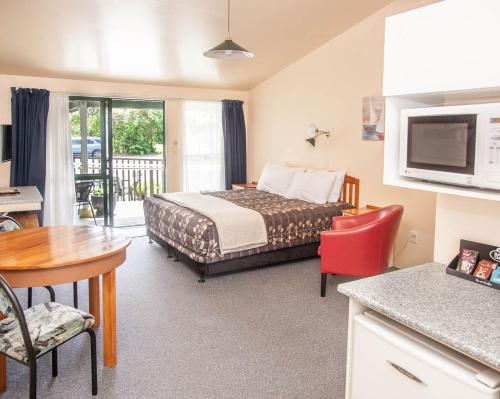 une chambre d'hôtel avec un lit, une table et des chaises dans l'établissement Goldmine Motel, à Waihi
