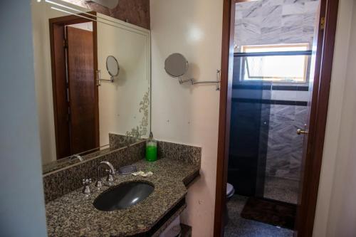 a bathroom with a sink and a mirror and a shower at POUSADA DONA DORA 2 in Piumhi