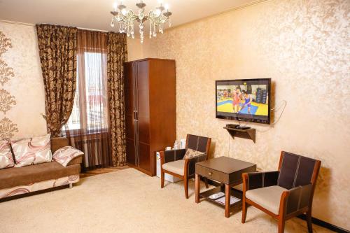 a living room with a couch and a tv on the wall at Totem Hotel in Shymkent