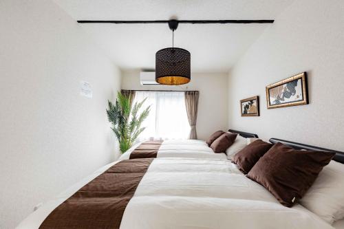 a large bed with brown pillows in a bedroom at Prestige Suites Osaka Abiko in Osaka