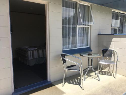 a patio with two chairs and a table and a window at Alma Motel in Oamaru