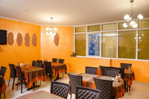 a restaurant with tables and chairs and windows at Totem Hotel in Shymkent