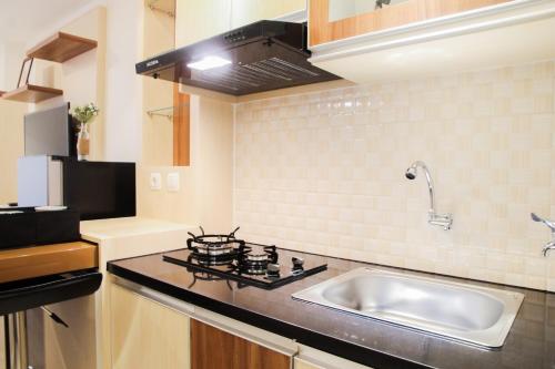 a kitchen with a sink and a stove at Comfortable Studio Apartment Grand Kamala Lagoon By Travelio in Pulosirih