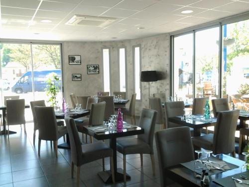 a dining room with tables and chairs and windows at Hôtel le midi in Montaigu-de-Quercy