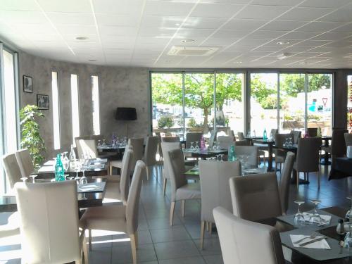 un comedor con mesas, sillas y ventanas en Hôtel le midi, en Montaigu-de-Quercy