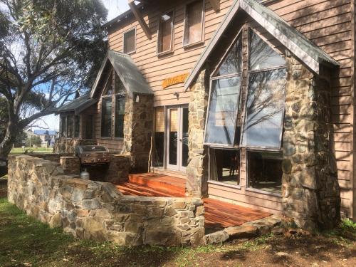 a house with a stone retaining wall around the front porch at Square Bear in Dinner Plain