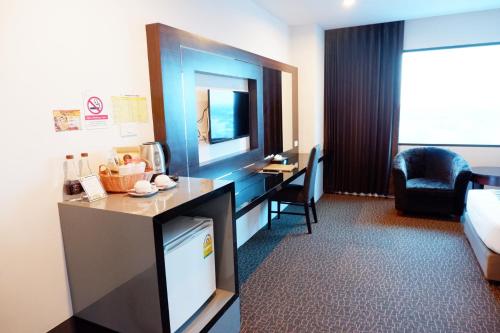a hotel room with a television and a bed and a desk at Siam Oriental Hotel in Hat Yai