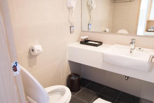 a bathroom with a sink and a toilet and a mirror at Saipan World Resort in Susupe