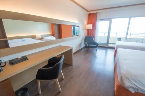 a hotel room with a desk and two beds at Saipan World Resort in Susupe