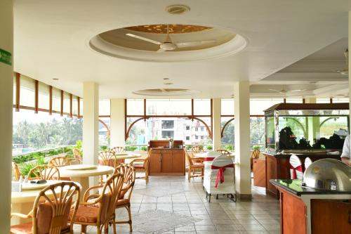 a dining room with tables and chairs and windows at Maurya Rajadhani in Trivandrum