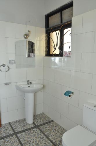 a white bathroom with a sink and a toilet at Trendy apartments in Entebbe