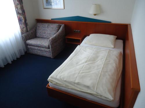 um pequeno quarto com uma cama e uma cadeira em Centralhotel Ratingen em Ratingen