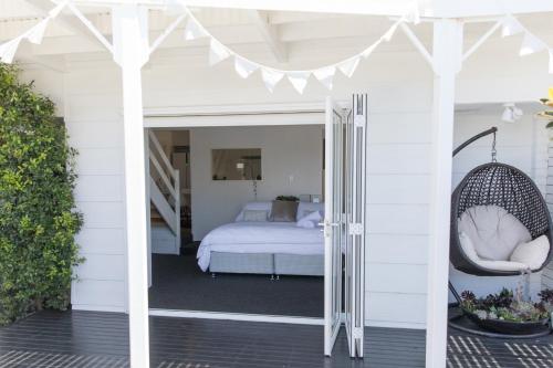 eine Veranda mit einem Bett und einer Schaukel in der Unterkunft White Beach Cottage in Lake Cathie