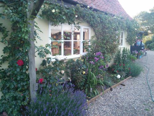 a house with flowers in front of a window at Brick Kiln Apartment in Campsea Ashe