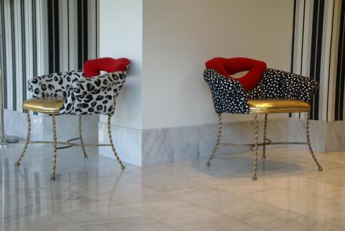 two chairs with red seats sitting next to a wall at Hotel Sitges in Sitges