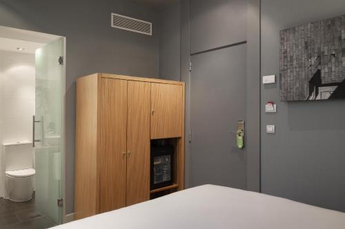 a bedroom with a wooden cabinet and a fireplace at Petit Palace Tres Cruces in Madrid