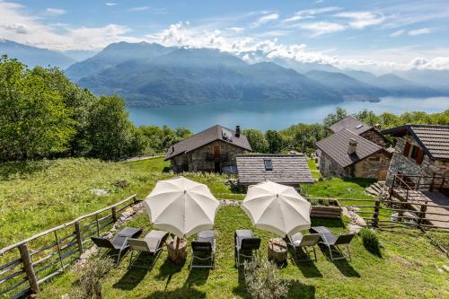 two umbrellas and chairs on a hill with a lake at Agriturismo Da Attilio in Cannobio