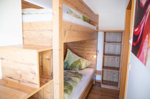 a bunk bed in a room with wooden walls at Himmelsbögen und Apartments mit Seeblick und Alleinlage in Weissensee