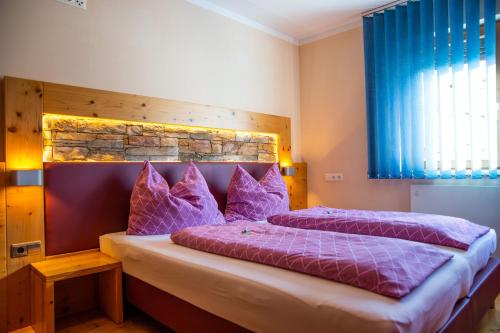 a bedroom with two beds with purple pillows at Himmelsbögen und Apartments mit Seeblick und Alleinlage in Weissensee