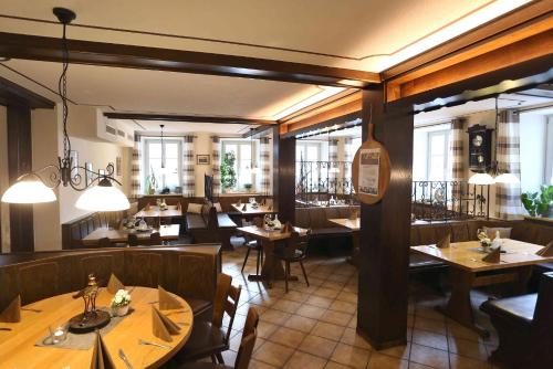 ゾンマーハウゼンにあるGasthof Hotel Weinbau "Zum Goldenen Ochsen"の木製のテーブルと椅子、窓のあるレストラン