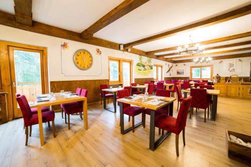 una sala da pranzo con tavoli in legno e sedie rosse di Fiemme Village a Bellamonte