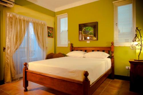 a bedroom with a bed with yellow walls and a window at Alongs Garden in Hengchun South Gate