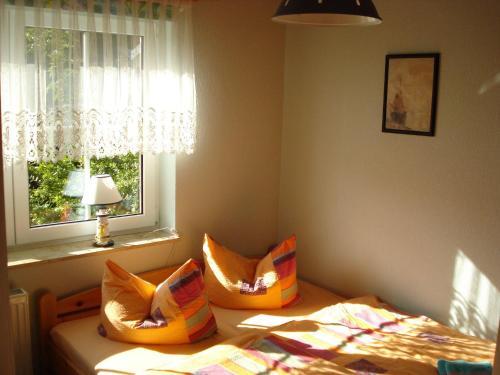 ein Schlafzimmer mit einem Bett mit orangefarbenen Kissen und einem Fenster in der Unterkunft Urlaub im ehemaligen Kapitänshaus in Dierhagen
