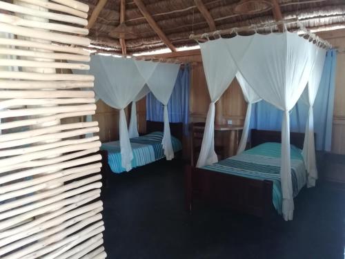 2 camas en una habitación con cortinas blancas en Hôtel Safari Vezo Anakao, en Anakao