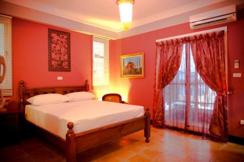 Un dormitorio con una cama con paredes rojas y una ventana en Alongs Garden en Hengchun Old Town