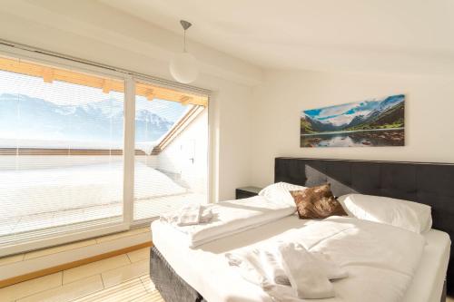 a bedroom with a bed and a large window at Ski-n-Lake - The Alps View Apartment in Zell am See