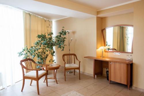 Habitación con escritorio, 2 sillas y espejo. en Apri Hotel Perm, en Perm