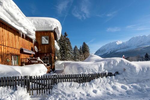 a house covered in snow next to a fence at Sportappartements in Bad Mitterndorf