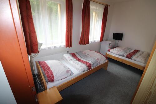 two beds in a room with windows and red curtains at Penzion U Elišky Bedřichov V Jizerských Horách in Bedřichov