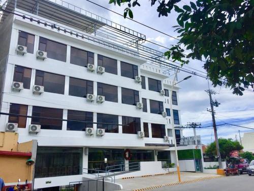 a white building with windows on a city street at Travelbee Seaside Inn in Tagbilaran City