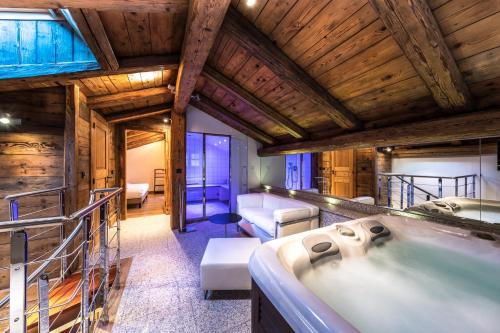 a large bathroom with a tub in a room with wooden ceilings at Hôtel Les Servages d'Armelle in Les Carroz d'Araches