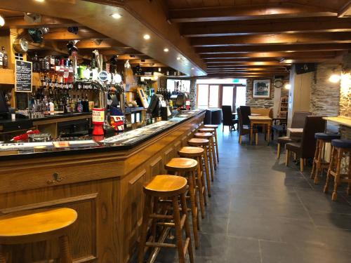 un bar con taburetes de madera en un restaurante en The Galleon Inn, en Fowey