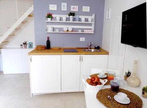una cucina con armadi bianchi e un bancone con lavandino di San Gregorio House a Bari