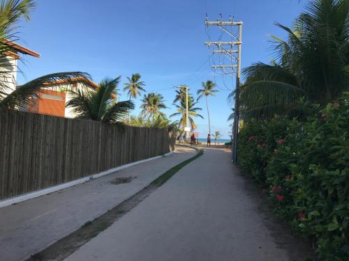 a street with a fence and palm trees on a beach at Imbassai Summer Flats Village in Imbassai