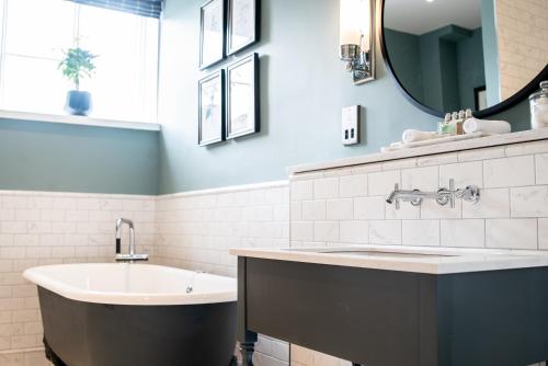 a bathroom with a tub and a sink and a mirror at The Highdown – Brunning and Price in Worthing