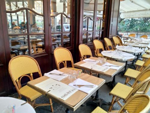 una fila de mesas y sillas en un restaurante en APPARTEMENT DE CHARME, en París