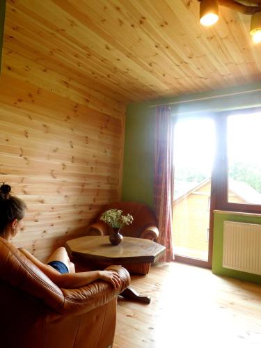 a woman sitting in a chair in a room with a table at Gospodarstwo Pytlówka Sokalski Michał in Tarczek