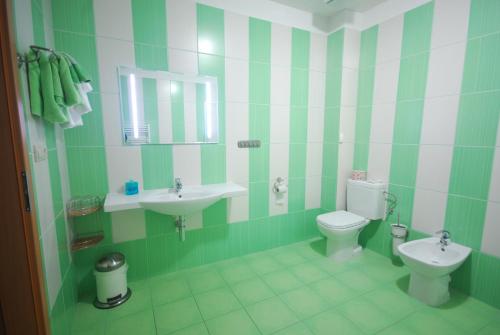 a green and white bathroom with a toilet and sink at Penzion Sidorovo in Ružomberok