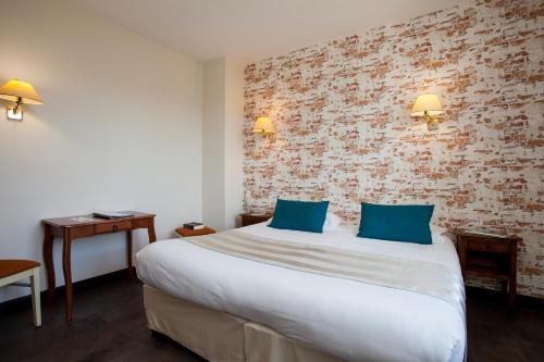 a hotel room with a large bed with blue pillows at Hôtel Restaurant Plaisance-Piscine couverte et chauffée- Proche Sarlat- in Vitrac