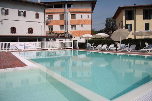 a large swimming pool with chairs and a building at Hotel Bel Sito in Peschiera del Garda